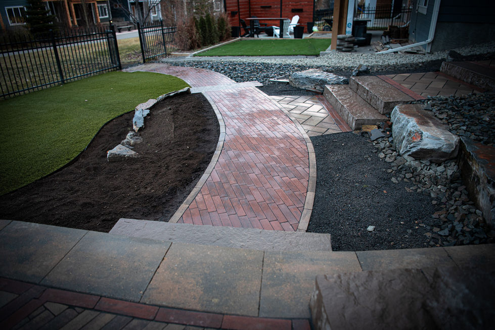Curved brick walkway leading to multi-level stone stairs with surrounding landscaping