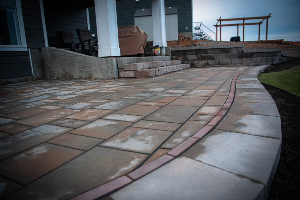 Stone patio with curved brick border and smooth hardscape finish after installation