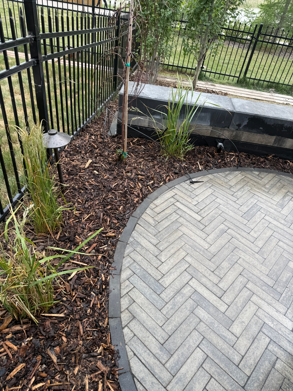 Herringbone paver patio detail with curved border, mulch bed, and ornamental grass planting