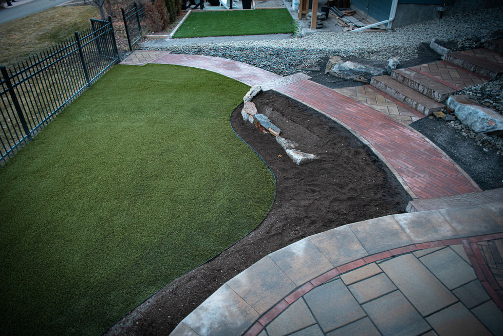 Curved garden pathway with artificial turf and defined stone border in landscape layout