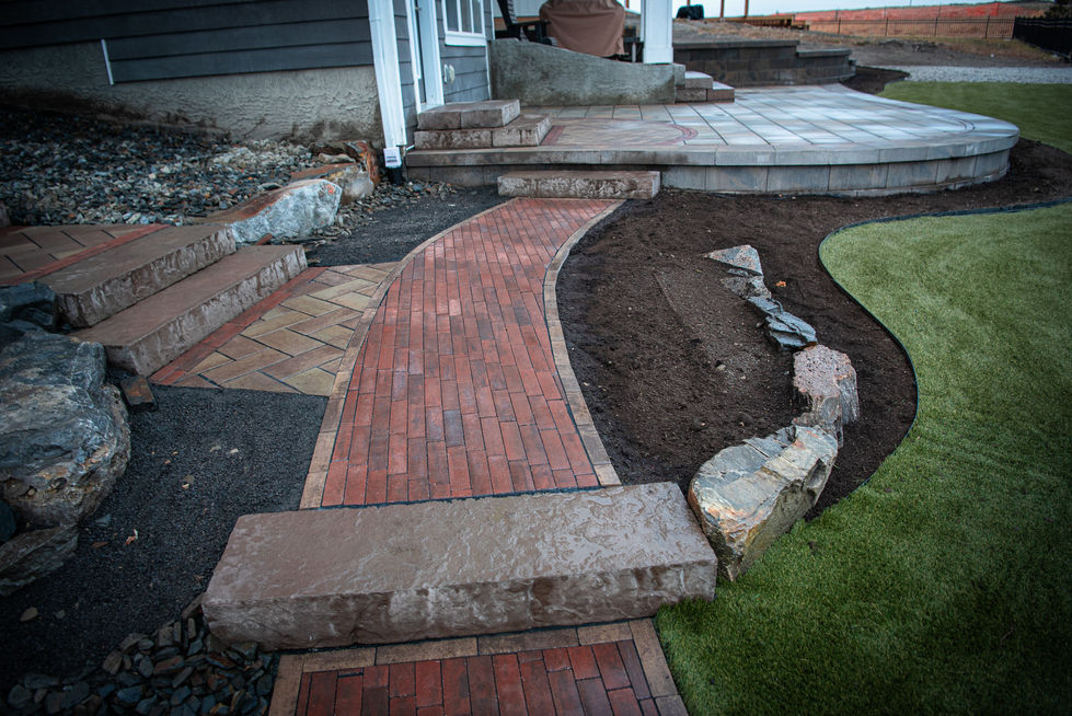 Curved brick walkway with stone border and surrounding garden bed landscaping