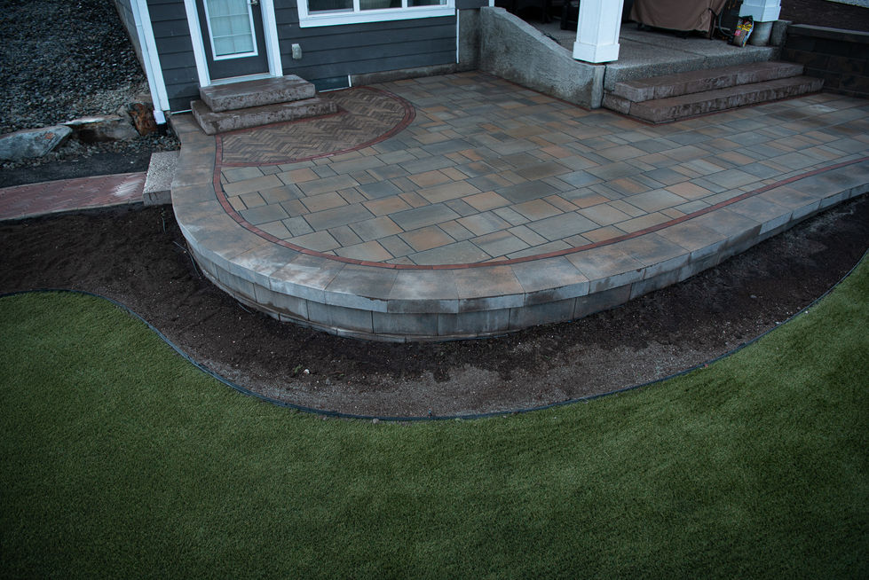 Stone patio with multi-level steps and surrounding lawn in residential landscaping project