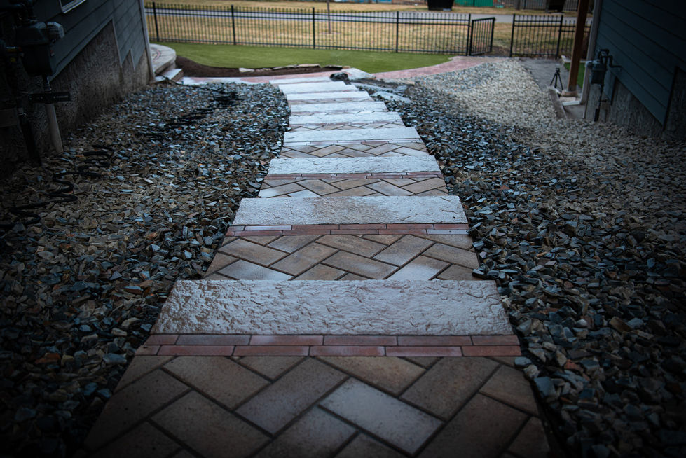 Stone pathway with herringbone inlay and gravel borders in residential landscaping project