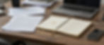 Desk with laptop, papers, notebook, and phone