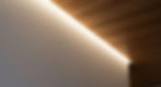 An abstract architectural detail showing integrated cove lighting between a Japanese cypress ceiling and a white plaster wall.