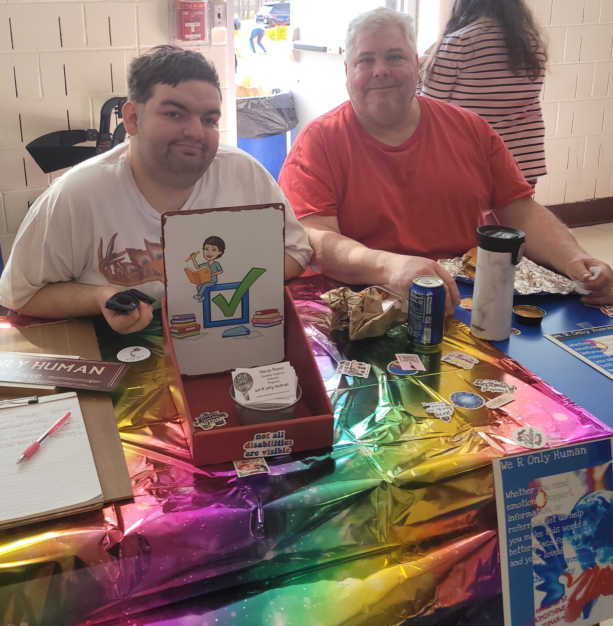 Two men at a We R Only Human community event table.