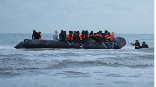 People wade through the sea towards a small boat in the Channel. Photograph: Gareth Fuller/PA