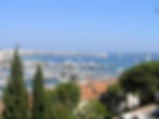 Looking down onto a harbour of large yachts, blue sea and and a cloudless blue sky at Cannes