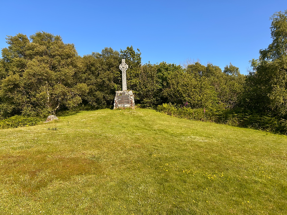 long range shot showing the memorial cross perched on a steep green hill, bathed in sunshine