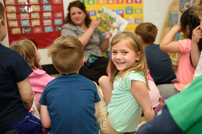 A preschool teacher reading a book to her students.