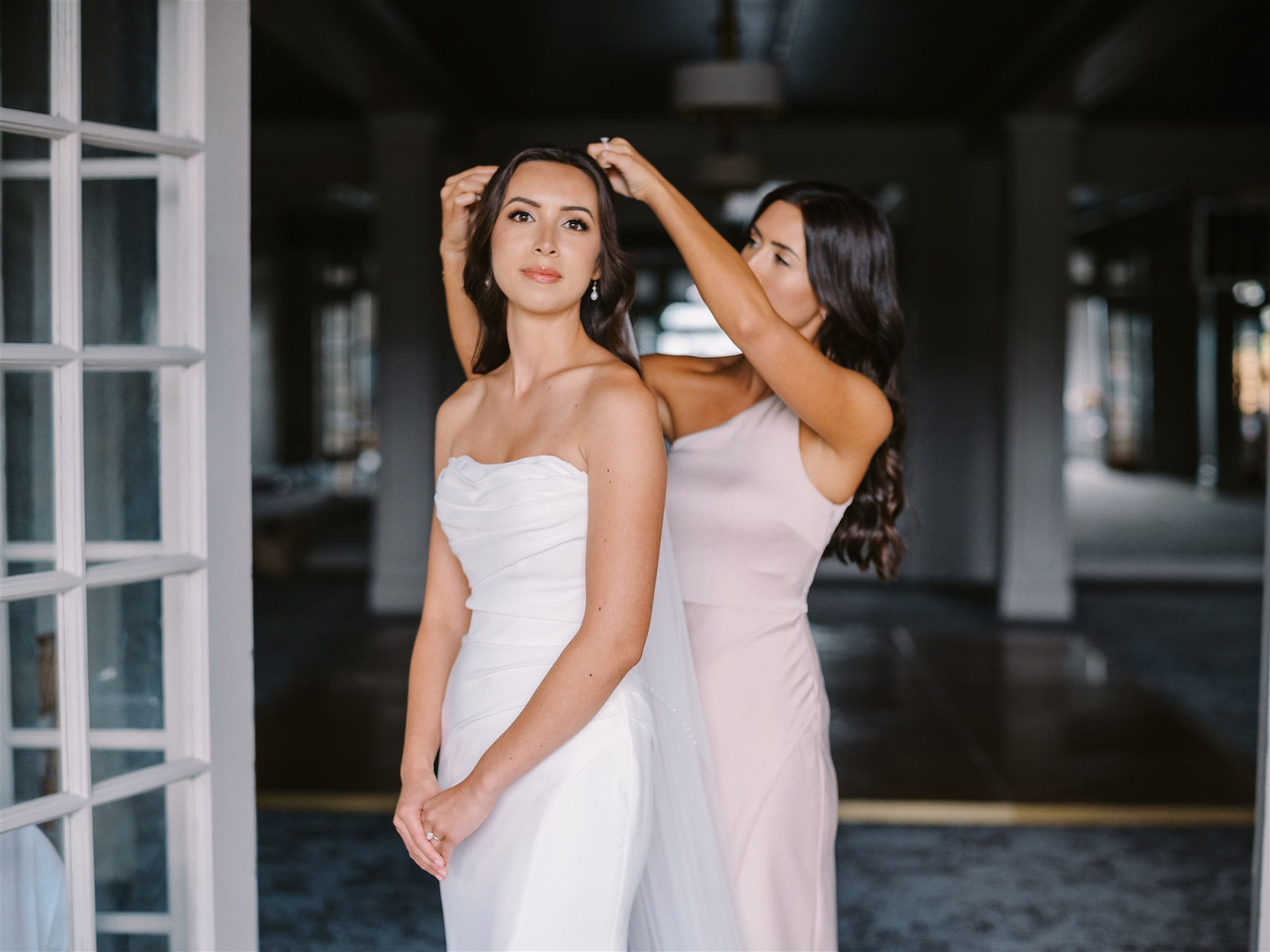 bridesmaid attaches a veil to a bride