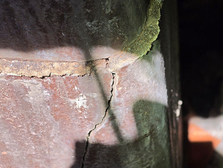 Cracked clay flue tile inside a masonry chimney following a chimney fire, showing hidden damage that requires professional inspection before continued fireplace use.