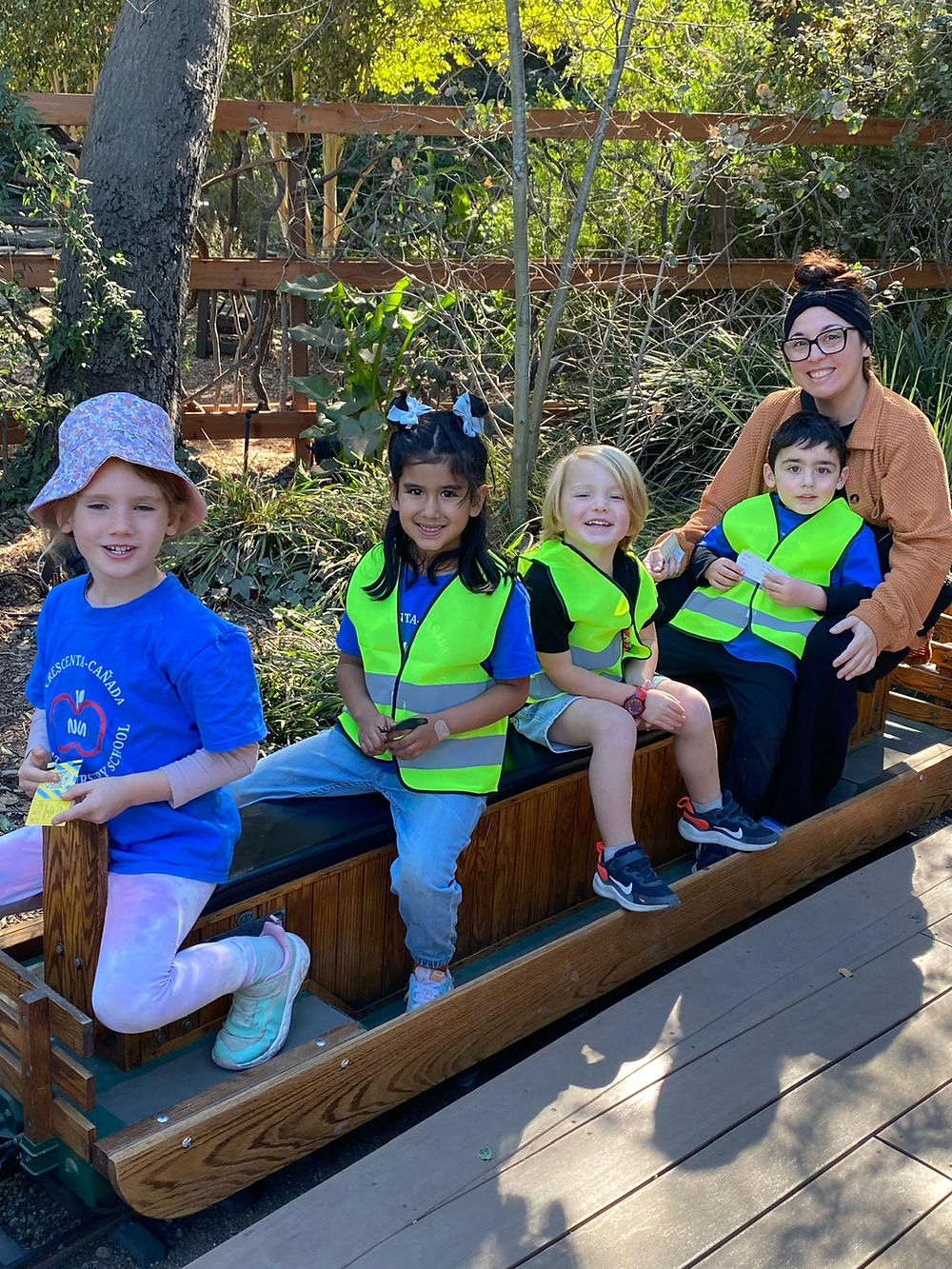 Four children in safety vests with an adult on a wooden ride