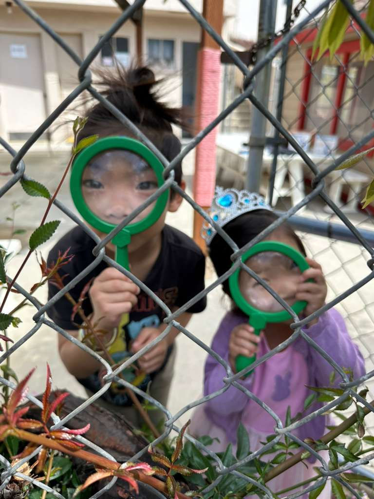 Two kids looking through oversized toy magnifying glasses.