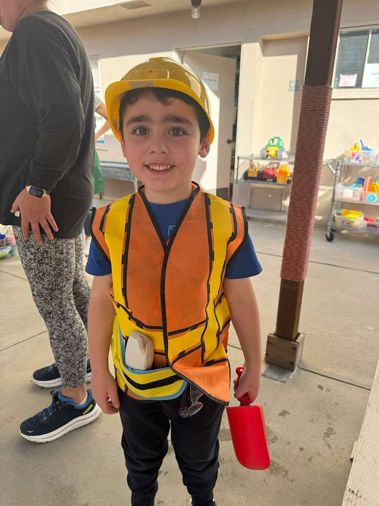 Smiling boy in yellow hard hat and orange safety vest