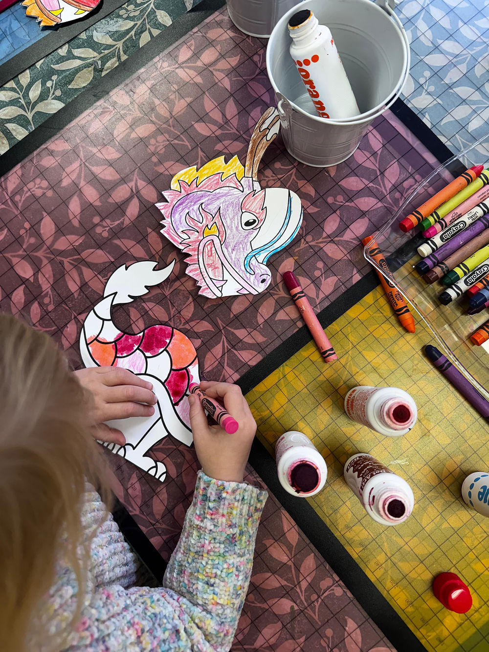 Children color in their paper dragon craft for Lunar New Year.