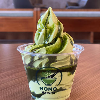 Matcha soft serve in a cup with Momo Matcha logo on display