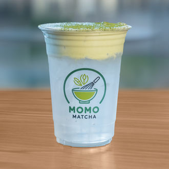 Iced Momo Matcha drink with logo in a plastic cup on a table