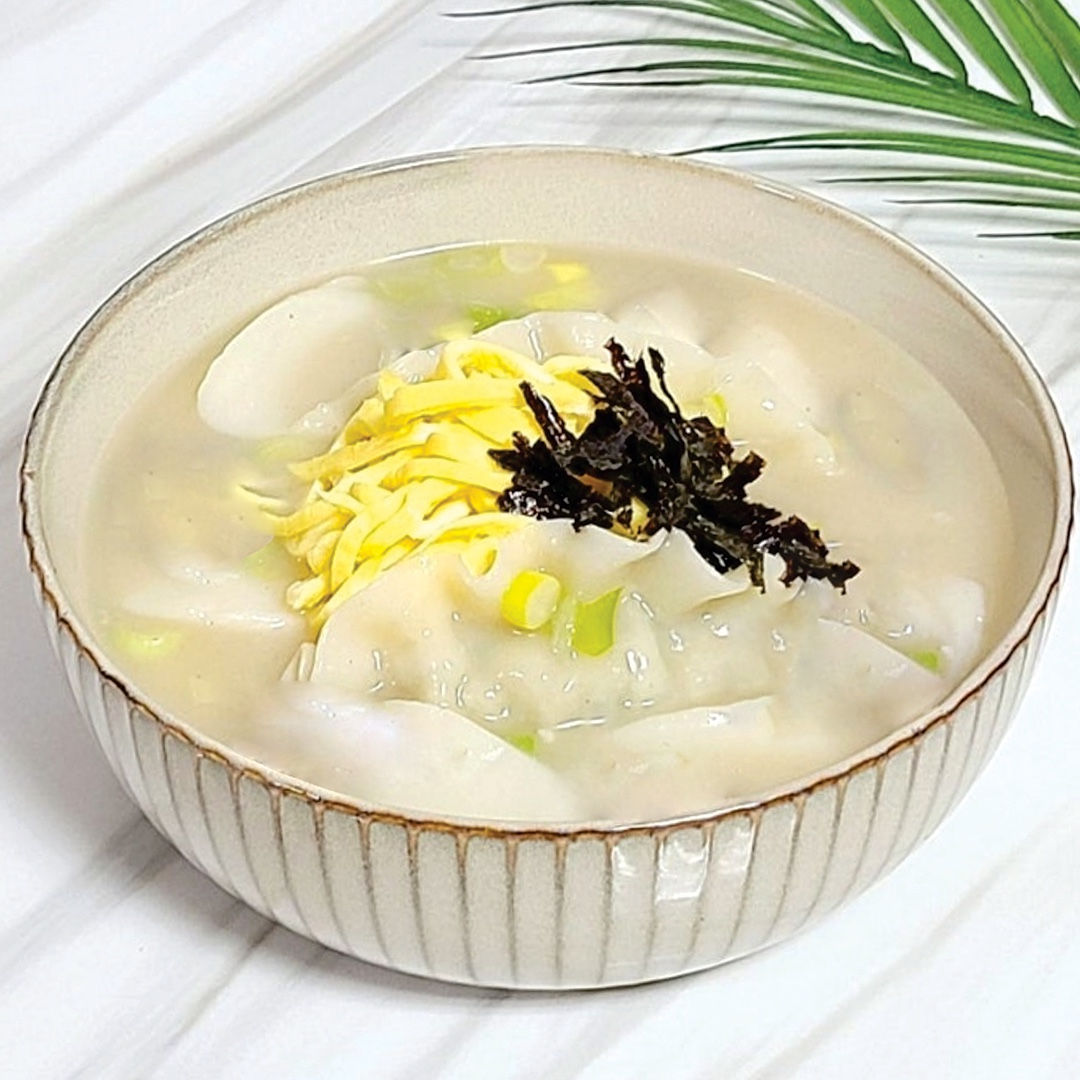 Delicious Korean mandoo Rang soup in a ceramic bowl with garnish.