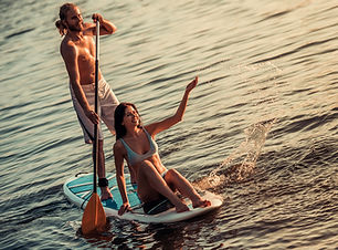 Beautiful young couple is talking and smiling while SUP surfing on the river_edited.jpg