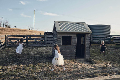 Wedding photography, flower girls play a game in a paddock, late afternoon sun