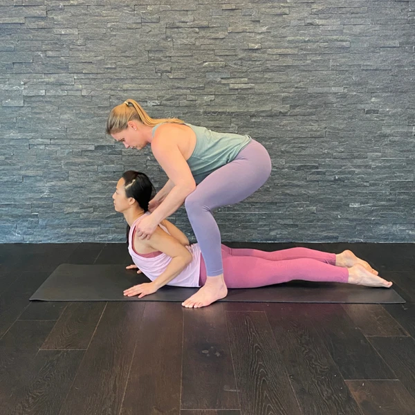 Rubber Band Method® Pigeon Pose Spinal Lengthening hands-on yoga assist technique.