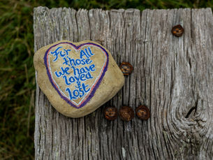 Memorial stone with the words "For All Those We Have Loved and Lost," representing remembrance, sympathy, grief, and honoring loved ones after a loss.