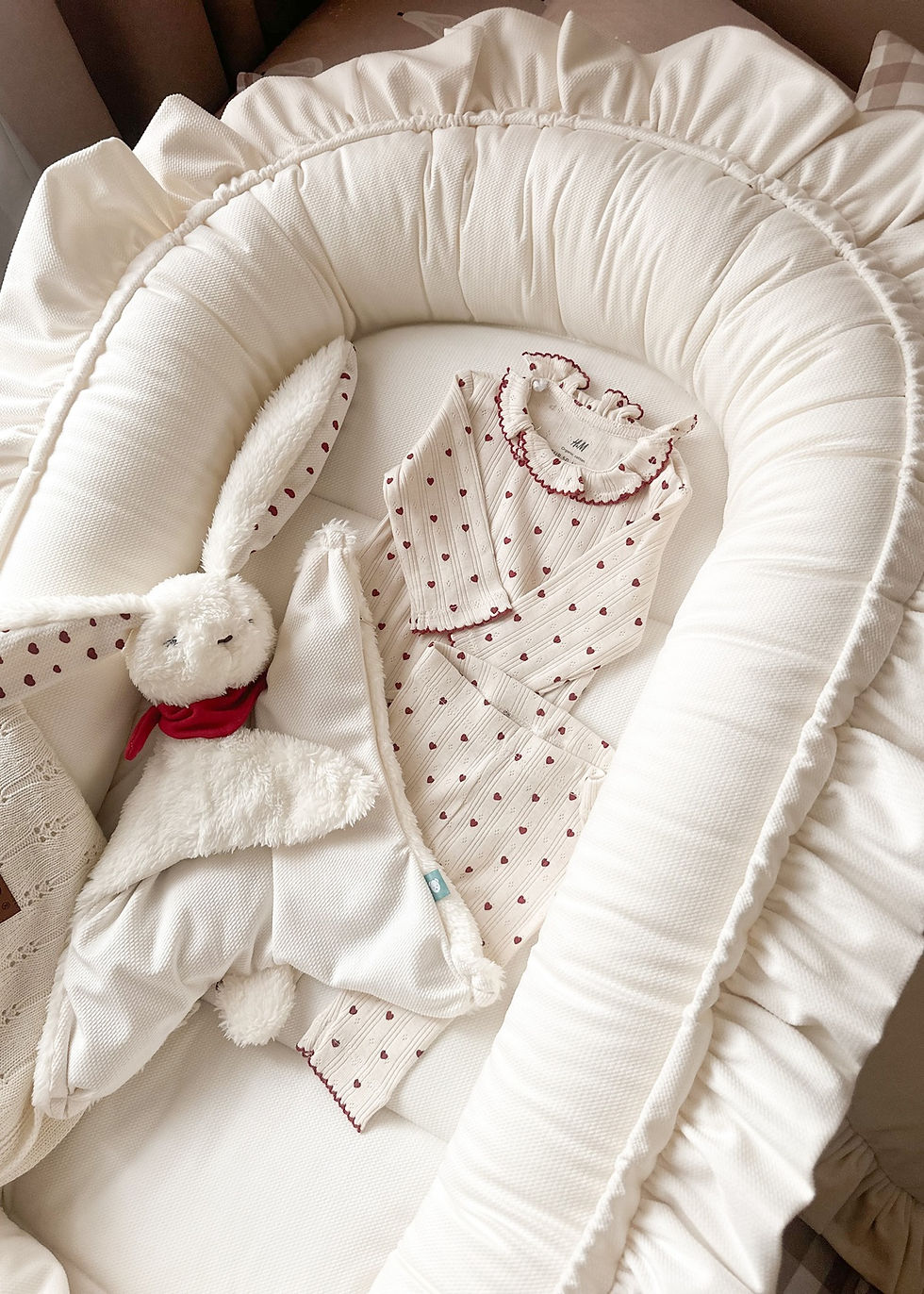 Thumbnail: Off white velvet baby nest cocoon with decorative ruffle placed in nursery crib