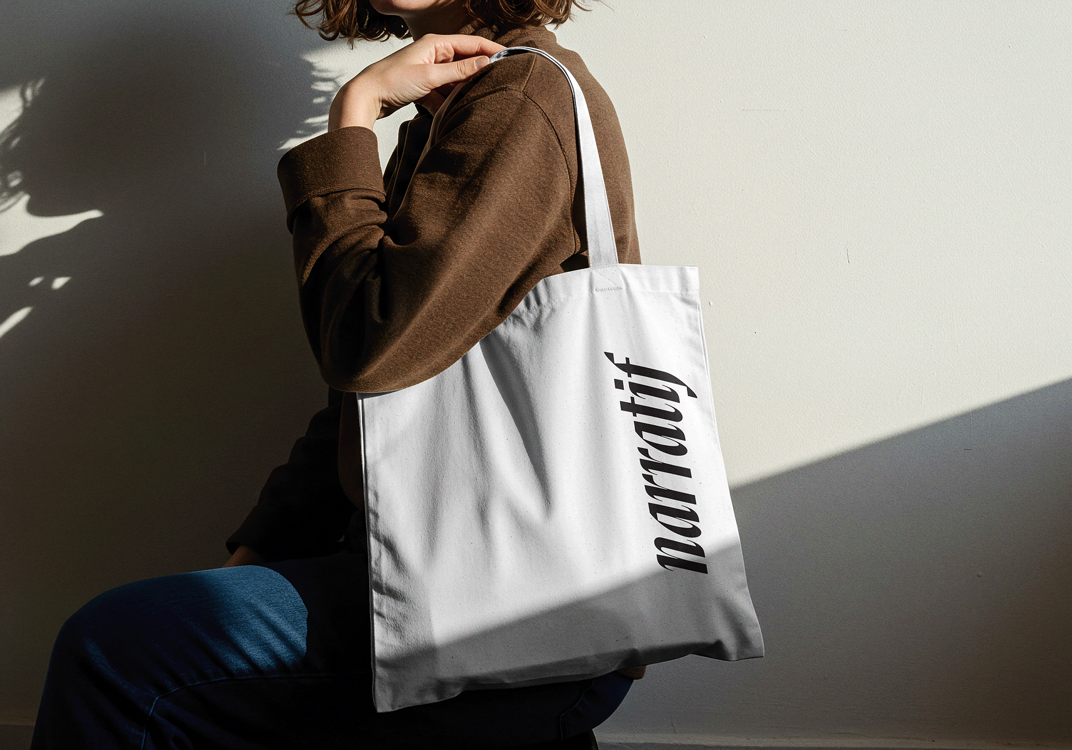 Woman holding a white tote bag with the word narratif printed on it.