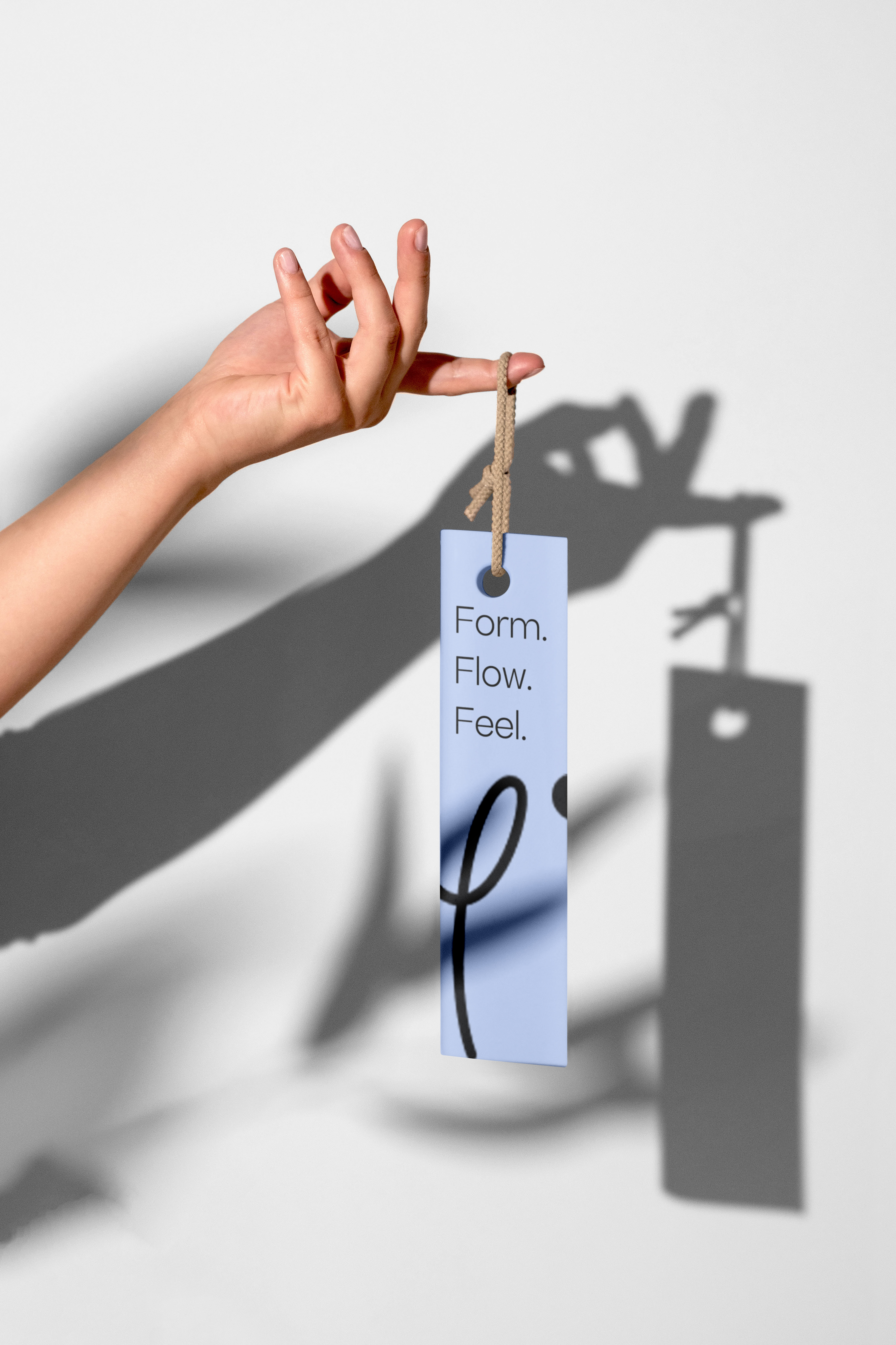 Hand holding a bookmark that reads Form, Flow, Feel with a shadow.