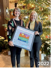 Two women hold framed artwork and member signatures thanking Edgewood Tahoe for supporting BGCLT.