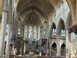 Interior view of a church looking towards the sanctuary with pews and stained glass windows