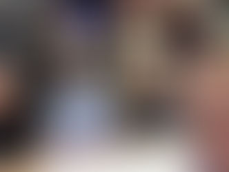 Group of four people sat around a table smiling a camera with shelves of books in background.