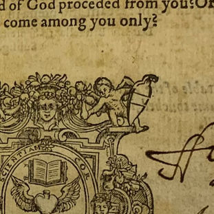 Photo of part of a title page with a large printer's device. The inscription is in black ink on either side of the device.