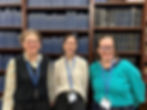 Group of women standing in front of bookcases. All are smiling and bespectacled and wearing blue lanywards.