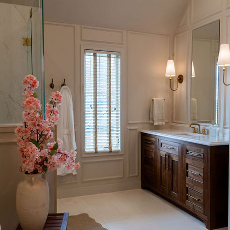 Elegant primary bathroom remodel with custom wood vanity, paneled walls, freestanding tub, and soft neutral finishes in a luxury Kansas City home.