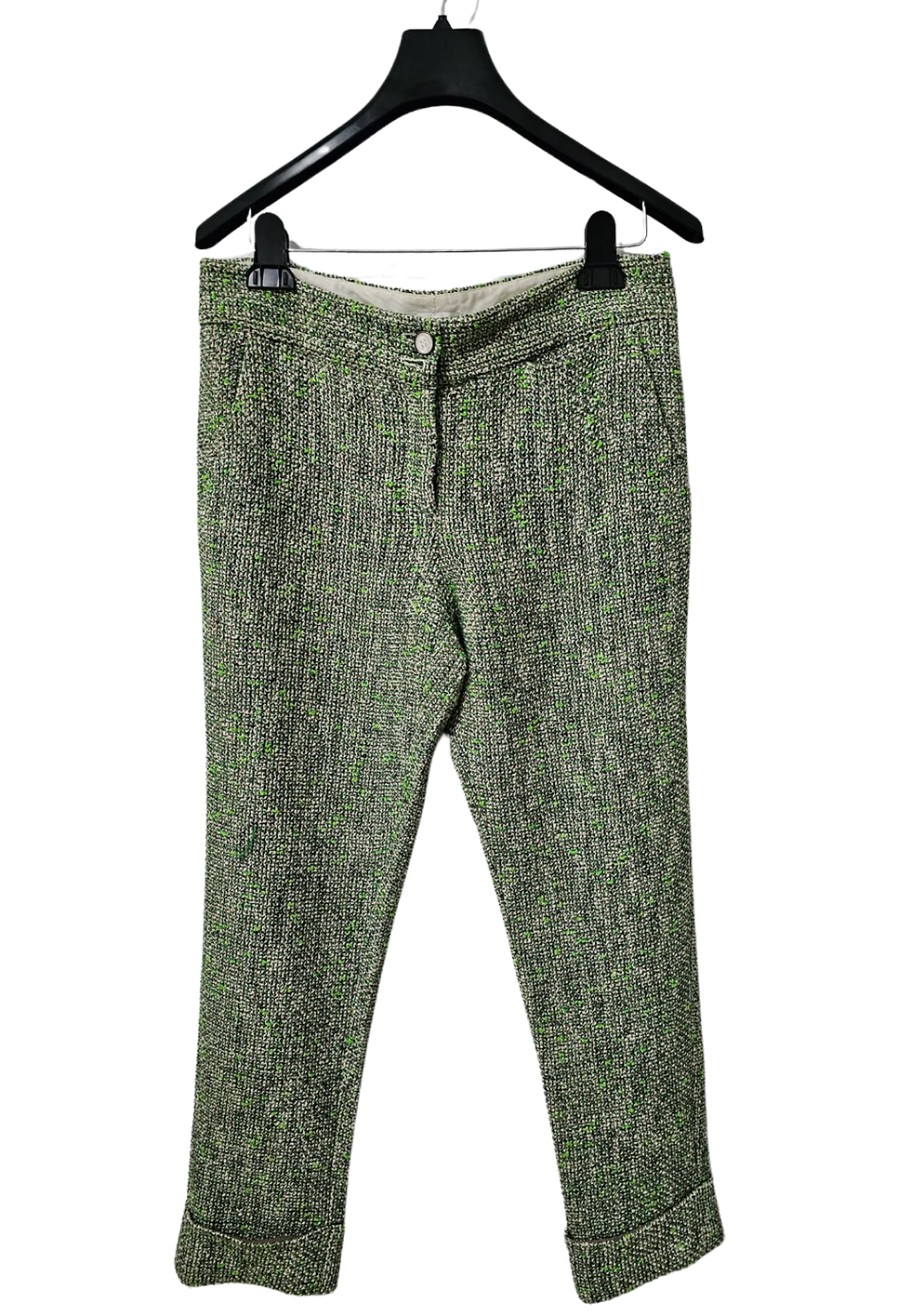 Green tweed pants hanging on a black hanger, white background, close-up.