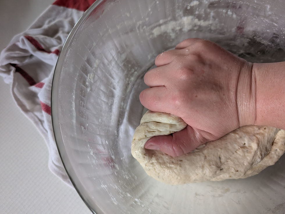 hand kneading bread dough in bowl