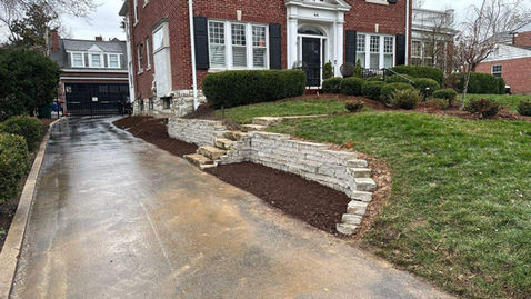 A St.Louis residence with fresh landscaping, including mulch and a natural stone retaining wall.