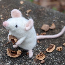 White needle-felted mouse holding nut shell 2023 hand crafted by Cinnamin Herring