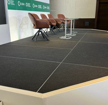 Close-up of raised conference stage with black stage deck and panel seating at LBMA 2024