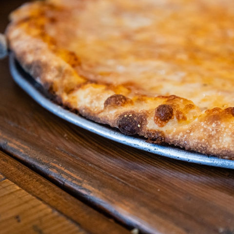 Close up photo of crust on a freshly cooked cheese pizza at Pizzoodles Pizza & Pasta Co.