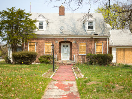 Vacant residential property with visible deferred maintenance and compliance concerns