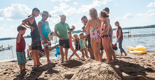 families building a turtle sculpture out of sand on the beach