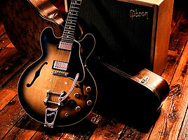This is a picture of a Beautiful Gibson F Hole BB King Guitar that is leaning against its case.