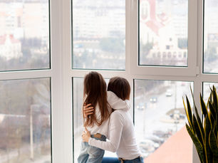 Madre con su hija asomadas por una ventana