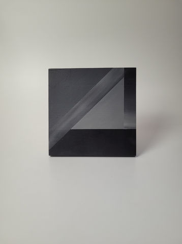 holzobjekt aus geometrisch angeordnetem holz in schwarz und naturholz, minimalistische wandarbeit
