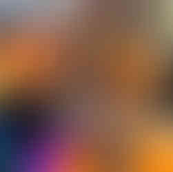 A toddler sits intently at an arcade race car game, gripping the steering wheel and looking at the screen, though the game is not active.