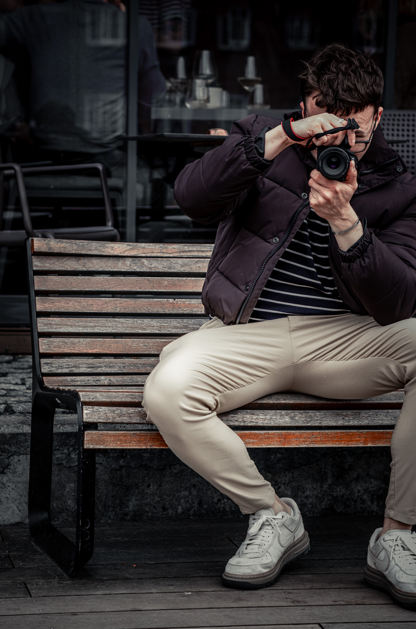 man sitting on bench taking photo on cameras