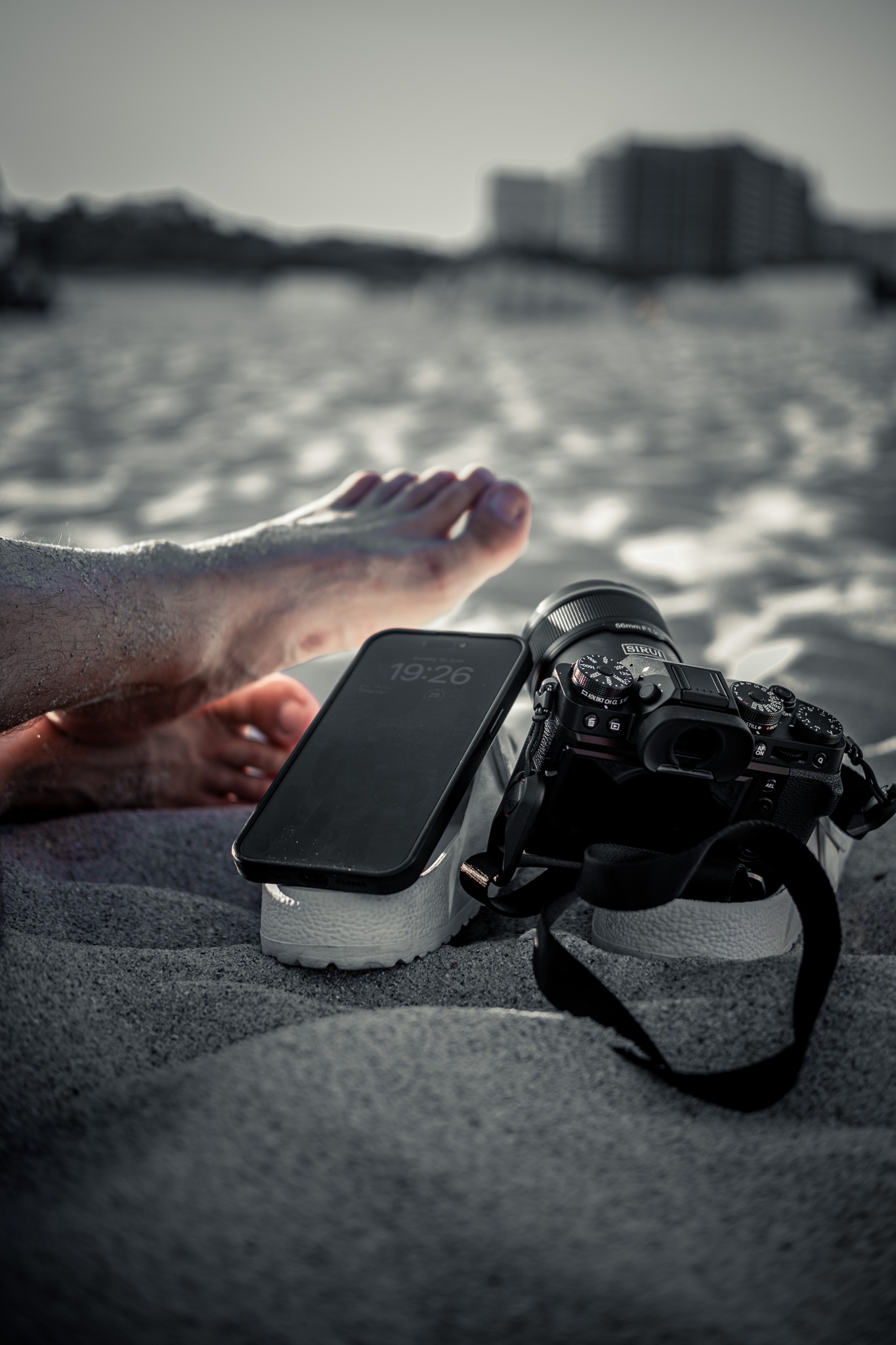 beach picture showing feet, phone, flip flops and camera